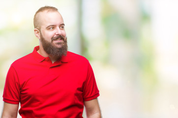 Young caucasian hipster man wearing red shirt over isolated background smiling looking side and staring away thinking.