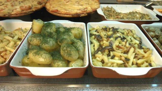 Side dishes in the supermarket.
Different side dishes are located on the showcase: fried potatoes with onions, boiled potatoes with greens, fried potatoes with mushrooms, small baked potatoes