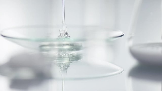 Transparent gel is falling onto a glas plade in a laboratory with a slow focus rack to a test tube