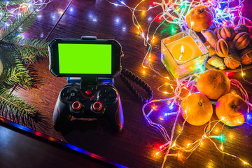 Game Pad with smartphone on black background table with colorful lights, Christmas New Year Composition. Smartphone gaming video game. Green screen. Gifs, gift. top view