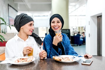 Two Muslim girls eat in a cafe celebrating international women's day