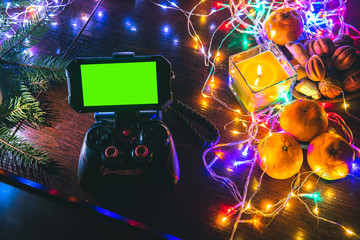 Game Pad with smartphone on black background table with colorful lights, Christmas New Year Composition. Smartphone gaming video game. Green screen. Gifs, gift. top view