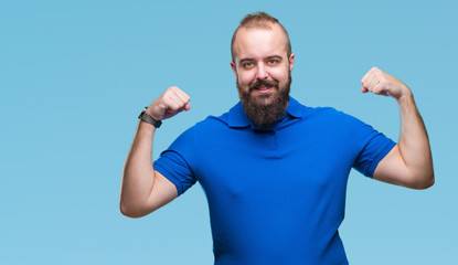 Fototapeta premium Young caucasian hipster man wearing blue shirt over isolated background showing arms muscles smiling proud. Fitness concept.