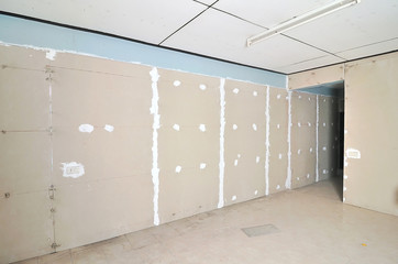 Plasterboards are installed on the wall in the construction site.