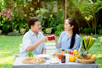 Asian Elderly couple Sitting in the home garden Rest from work throughout life taking care of health after retirement eating tea and coffee drinks appropriately Eat useful food Life insurance concept