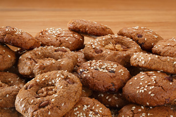 Homemade oatmeal cookies with nuts, chocolate chips and sesame. On a wooden background.