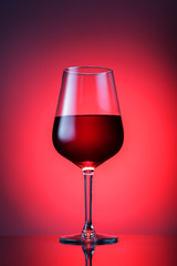 Glass of red wine on red background