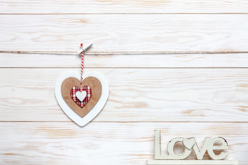 Wooden colorful heart on rope and letters Love. Concept for Valentine's Day, wedding, engagement and other romantic events. Top view, close-up, flat lay on white wooden background