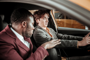 Young dark-eyed man feeling scarred while learning driving