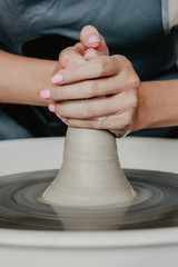 Creating a jar or vase of white clay close-up. Woman hands making clay jug.
