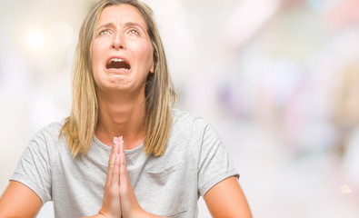 Young beautiful woman over isolated background begging and praying with hands together with hope...