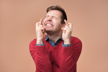 Young man making a wish isolated on brown background