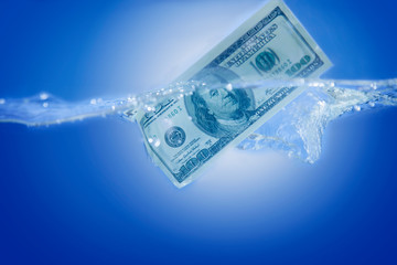 US Dollar sinking in water as symbol of global financiall crisis and uncertain future of international trade and investment.