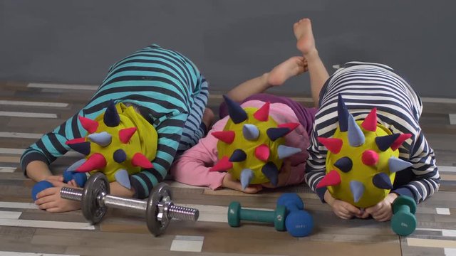 Cheerful children in carnival caps with colorful needles, like hedgehog, do gymnastics with dumbbells. Children enjoy winter vacations together. concept of traditional family holiday