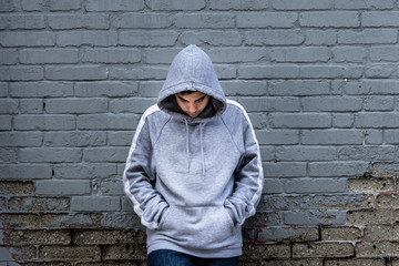 Lonely boy leaning against an urban wall