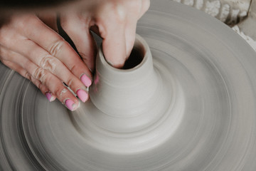 Creating a jar or vase of white clay close-up. Woman hands making clay jug.