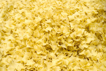 Yellow dry uncooked Quadretti pasta, square shaped pasta background, top view. 