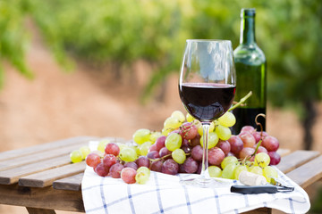 glass of red wine and ripe grapes on table