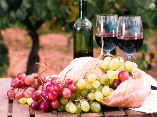 glass of red wine ripe grapes and bread in vineyard