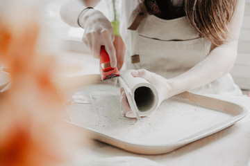 Woman making pottery. Close-up of process of sanding clay plate
