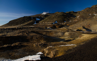 Fumarole fields of Iceland covered with yellow brimstone with boiling mud craters against the winter sky