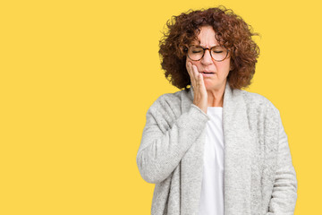 Beautiful middle ager senior woman wearing jacket and glasses over isolated background touching mouth with hand with painful expression because of toothache or dental illness on teeth