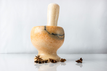star anise near a mortar on a white background