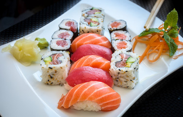 Sushi maki and California Roll with ginger and wasabi on a plate with chopsticks