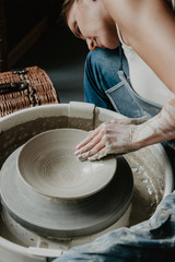 Creating a jar or vase of white clay close-up. Woman hands making clay jug.