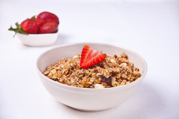 A plate with muesli and strawberries on a white background.