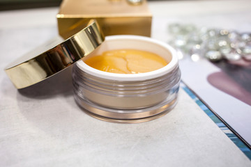 gold patches for the eyes in a jar with an open lid and a golden box on the background. beauty and personal care concept