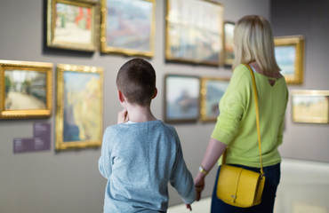 Mother and son regarding paintings in halls of museum