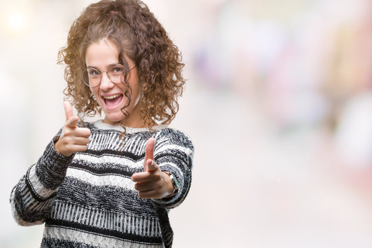 Beautiful brunette curly hair young girl wearing glasses over isolated background pointing fingers to camera with happy and funny face. Good energy and vibes.