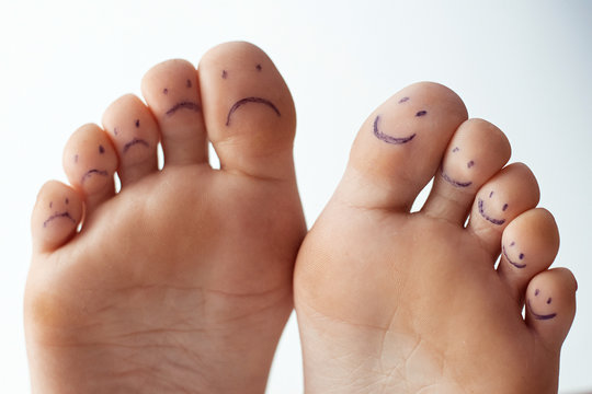 Female toes with painted smileys. Foot care concept.