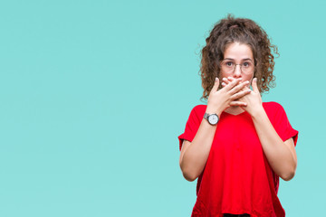 Beautiful brunette curly hair young girl wearing glasses over isolated background shocked covering mouth with hands for mistake. Secret concept.