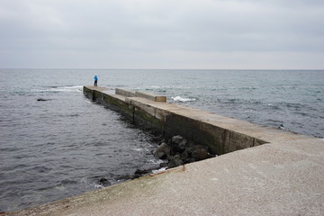 man stands on a concrete pier against the background of the sea
