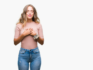 Beautiful young blonde woman over isolated background smiling with hands on chest with closed eyes and grateful gesture on face. Health concept.