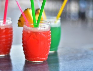 Fresh red and green cocktails with straws and with a piece of pineapple