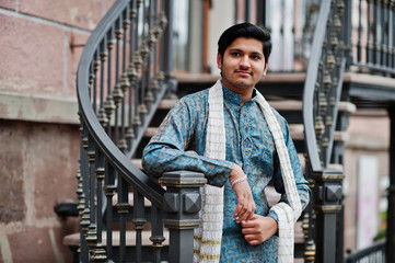 Indian man wear on traditional clothes with white scarf posed outdoor against iron stairs.