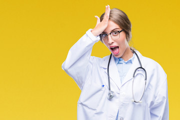 Beautiful young blonde doctor woman wearing medical uniform over isolated background surprised with...