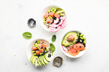 Fresh seafood recipe. Salmon gravlax poke bowl with fresh prawn, brown rice, cucumber, pickled sweet onion, radish, soy beans edamame portioned with black and white sesame. Food concept poke bowl