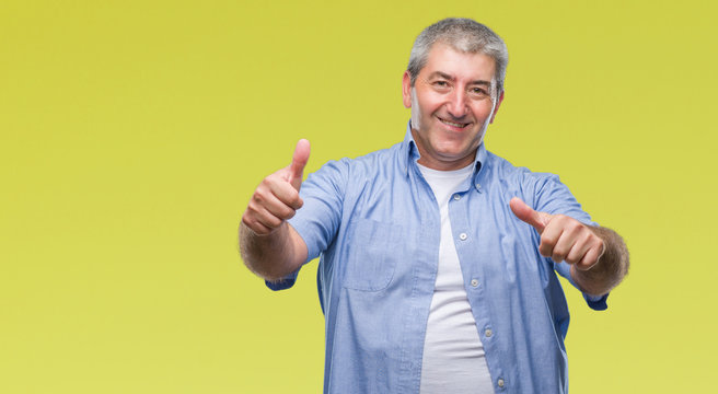 Handsome senior man over isolated background approving doing positive gesture with hand, thumbs up smiling and happy for success. Looking at the camera, winner gesture.