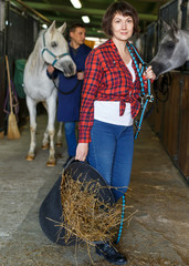 Positive female worker feeding horses