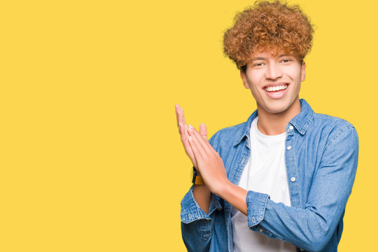 Young handsome man with afro hair wearing denim jacket Clapping and applauding happy and joyful, smiling proud hands together