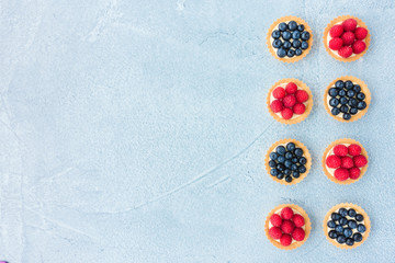 Blueberry and Raspberry Tartlets on Blue Concrete Background