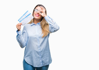 Young beautiful woman holding boarding pass over isolated background with happy face smiling doing ok sign with hand on eye looking through fingers