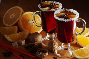 Two cups with ready mulled wine with anise, cinnamon and nuts around	