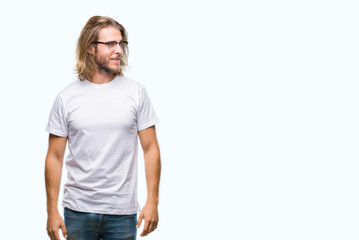 Fototapeta premium Young handsome man with long hair wearing glasses over isolated background looking away to side with smile on face, natural expression. Laughing confident.