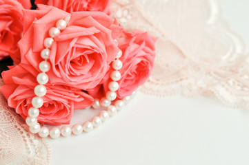 Delicate feminine theme. Pink coral roses trend color on a pale pink bra and pearl necklace on a...
