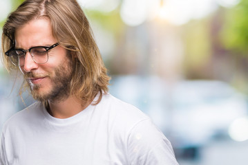 Young handsome man with long hair wearing glasses over isolated background with hand on stomach because nausea, painful disease feeling unwell. Ache concept.